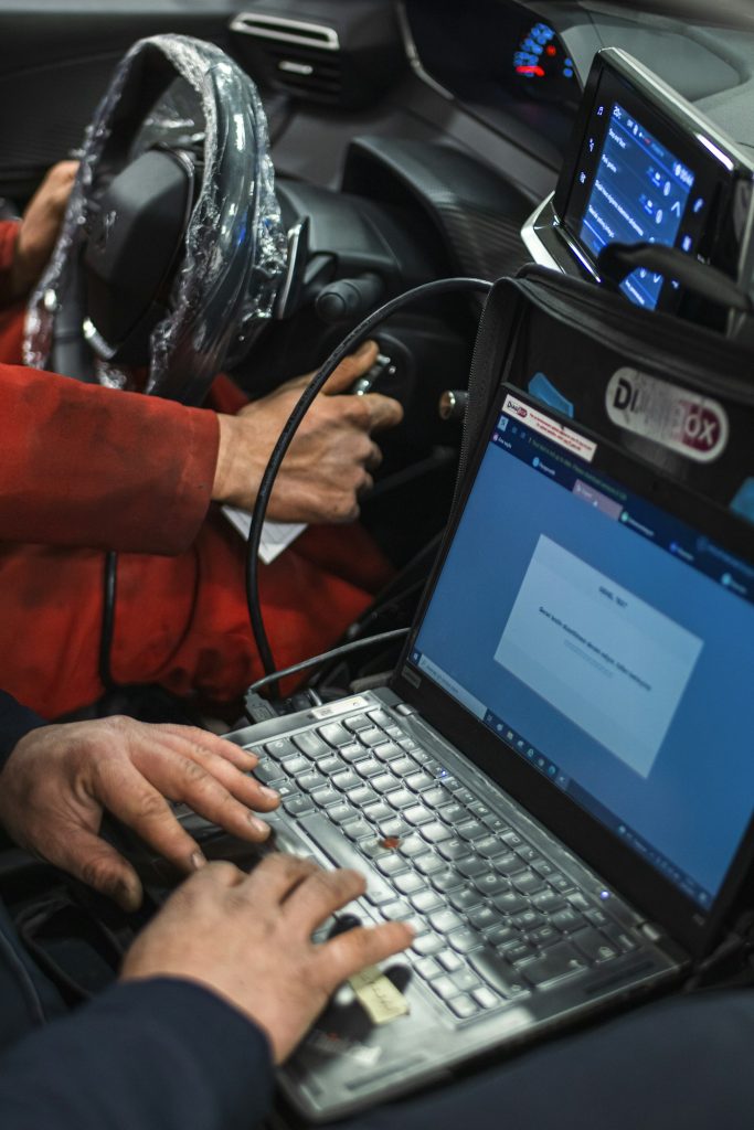 Technician running computer diagnostics from inside a car